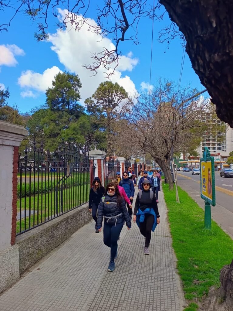 Grupo caminando por una vereda arbolada de Buenos Aires